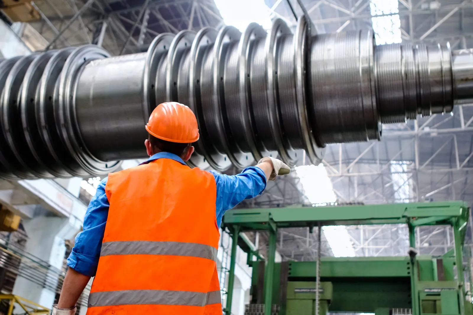 Technicien en équipements de protection devant un grand rotor dans un hall industriel